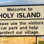 Sign saying: Welcome to Holy Island. Please use the visitors car park and help protect our village